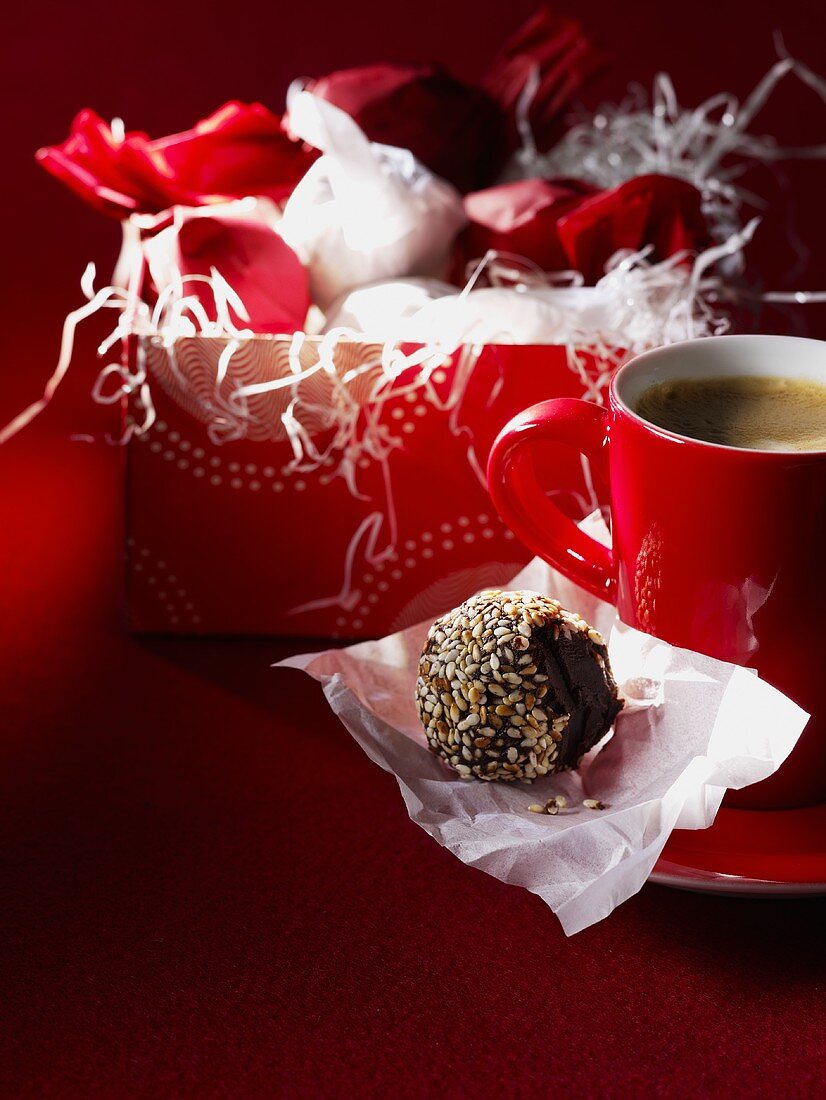 Sesame chocolate truffles in gift wrapping, cup of coffee