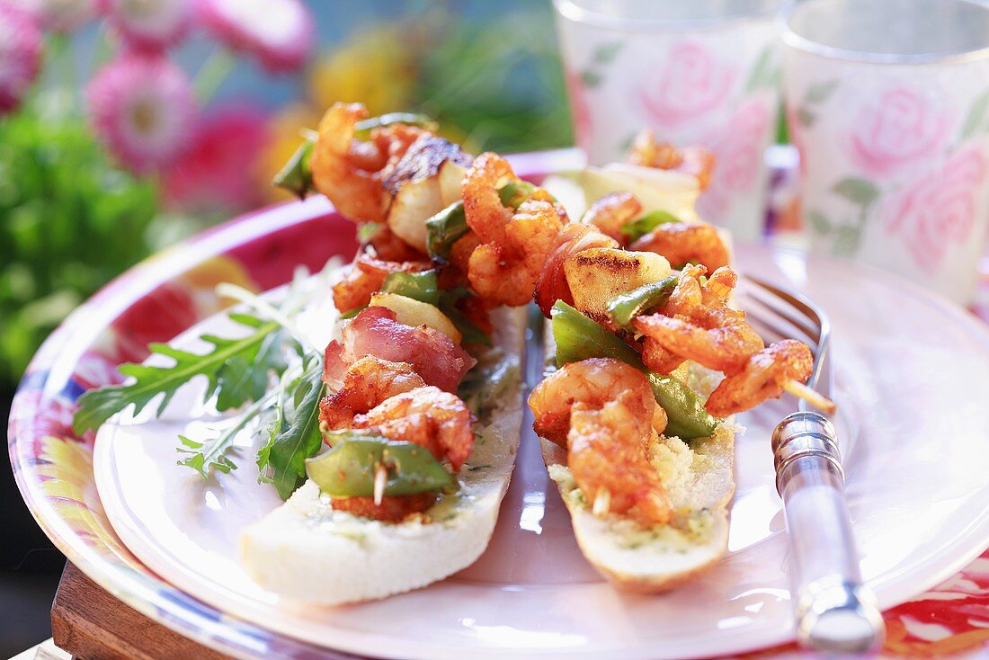 Prawn, vegetable and bacon kebabs on baguettes