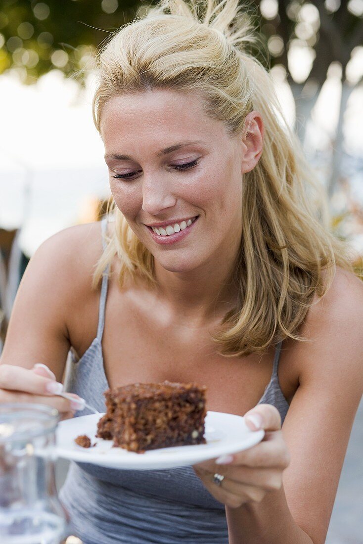 Junge Frau in sommerlicher Bekleidung isst ein Stück Kuchen