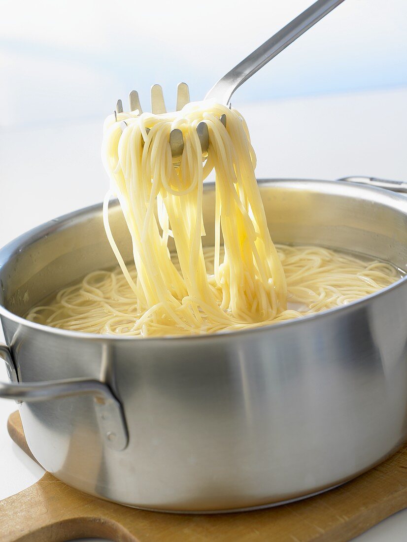 Spaghetti im Kochtopf und auf Spaghettiheber