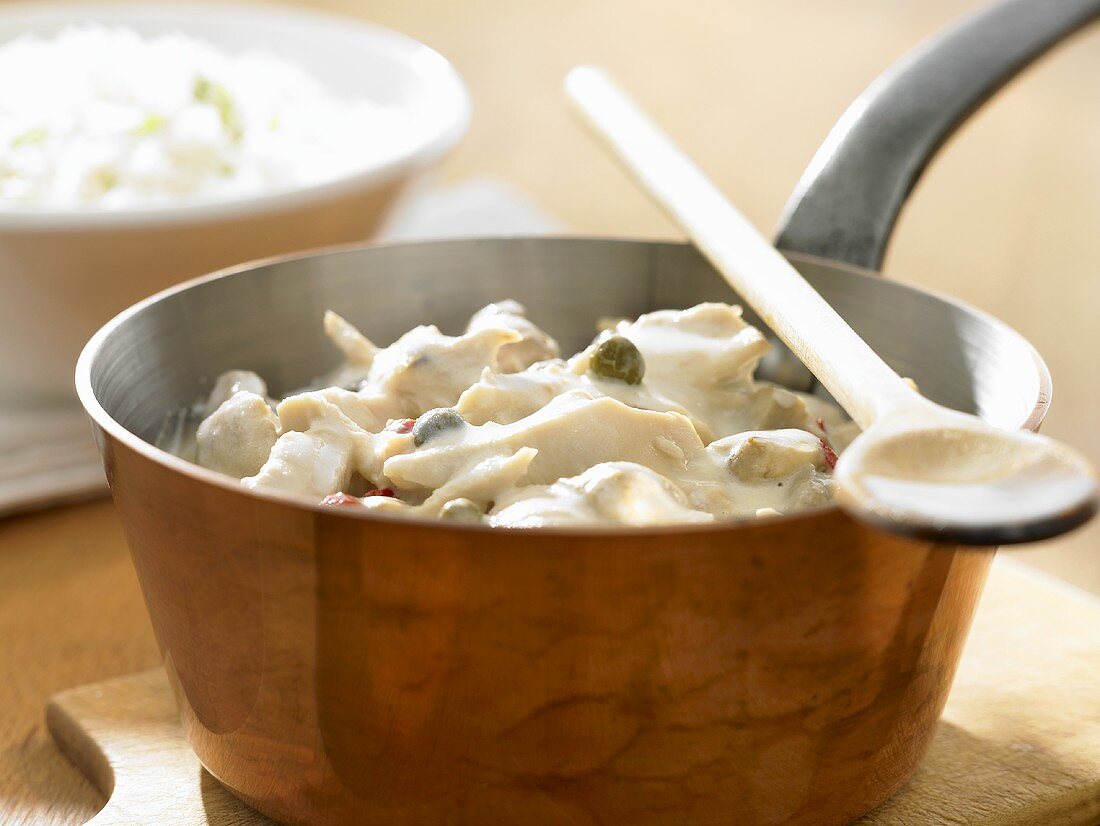 Chicken fricassee with capers and mushrooms, rice behind