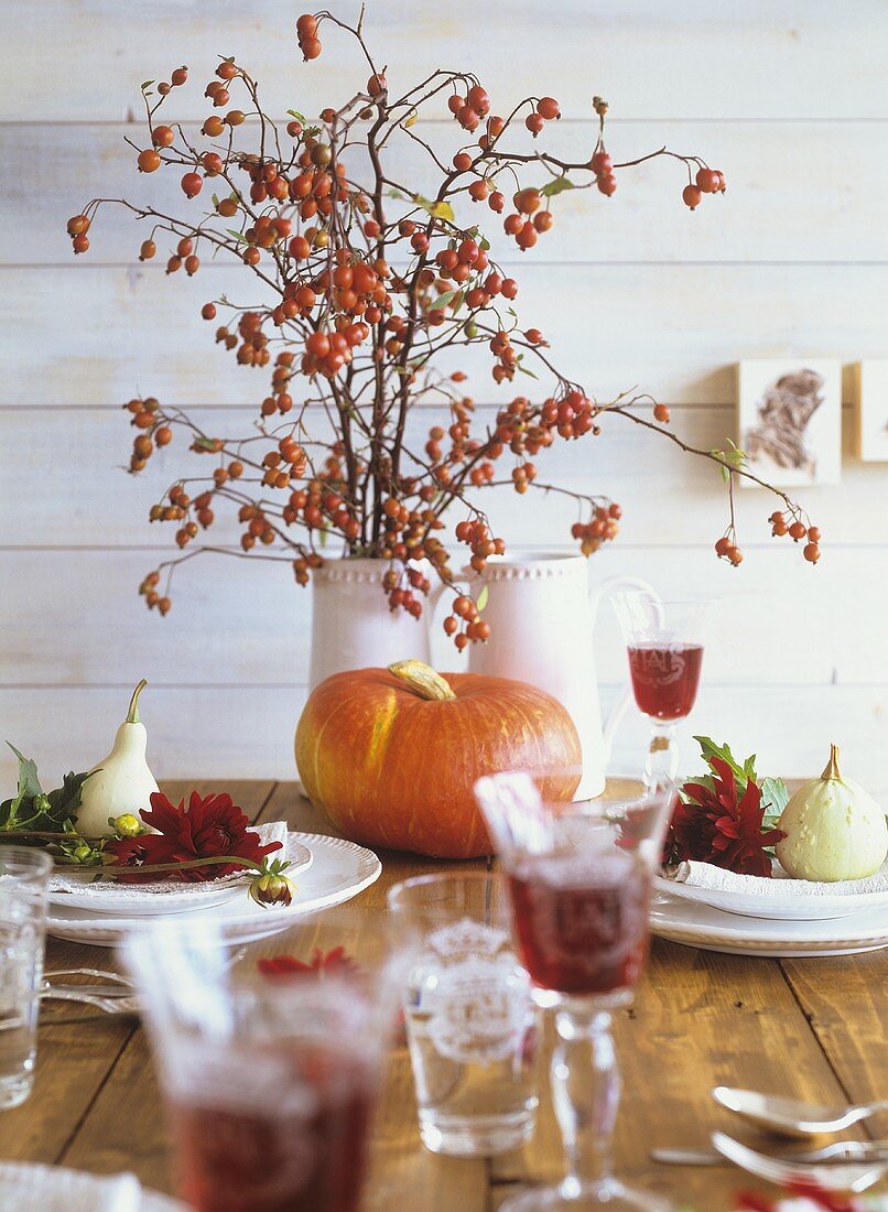 Herbstliche Tischdeko mit Kürbissen und Hagebuttenzweigen