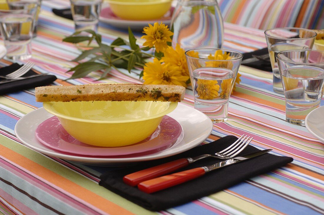 Gedeck mit Brot-Stick auf sommerlich gedecktem Tisch