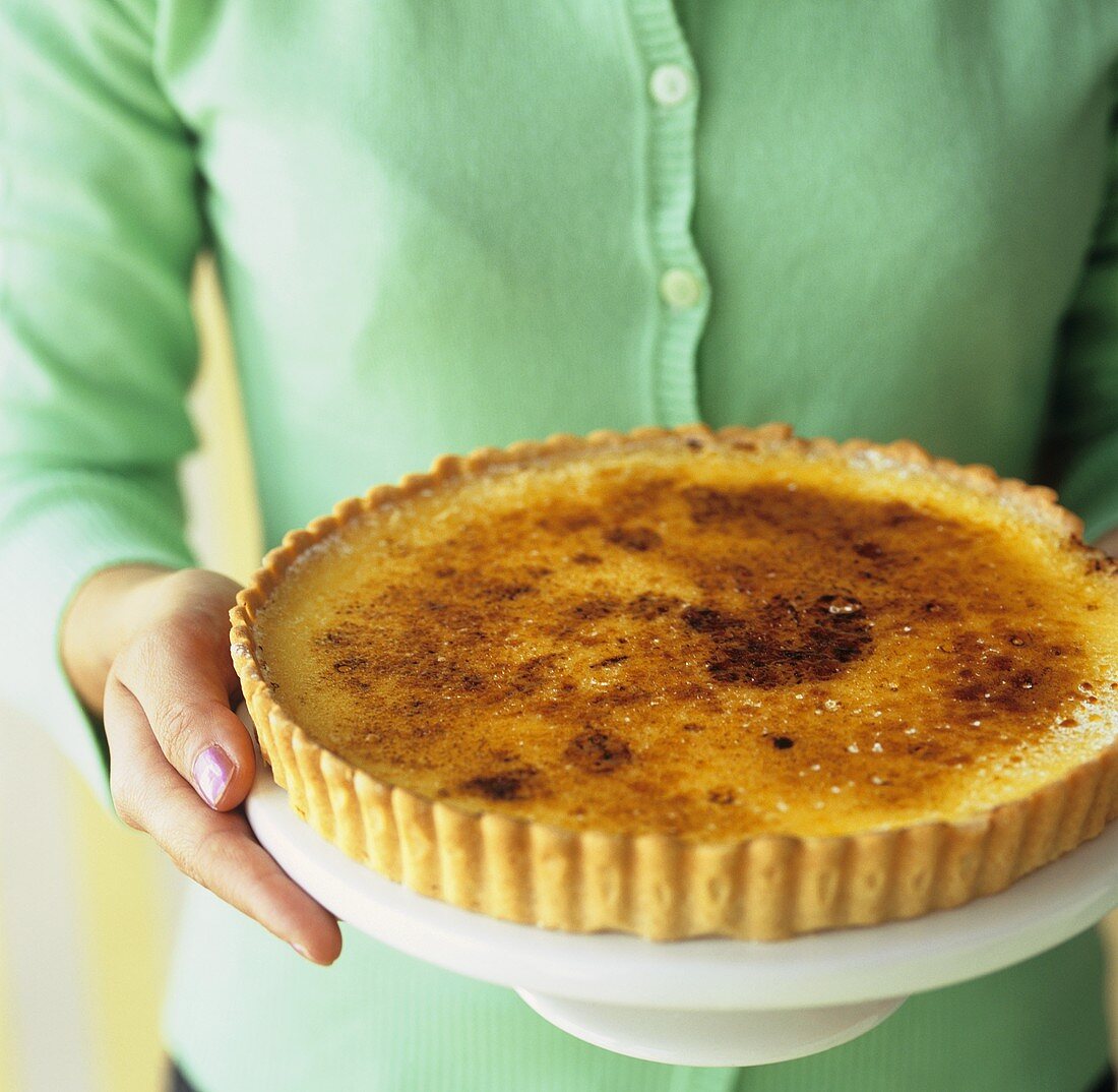 Frau hält eine Lemon Tarte (Zitronentorte)