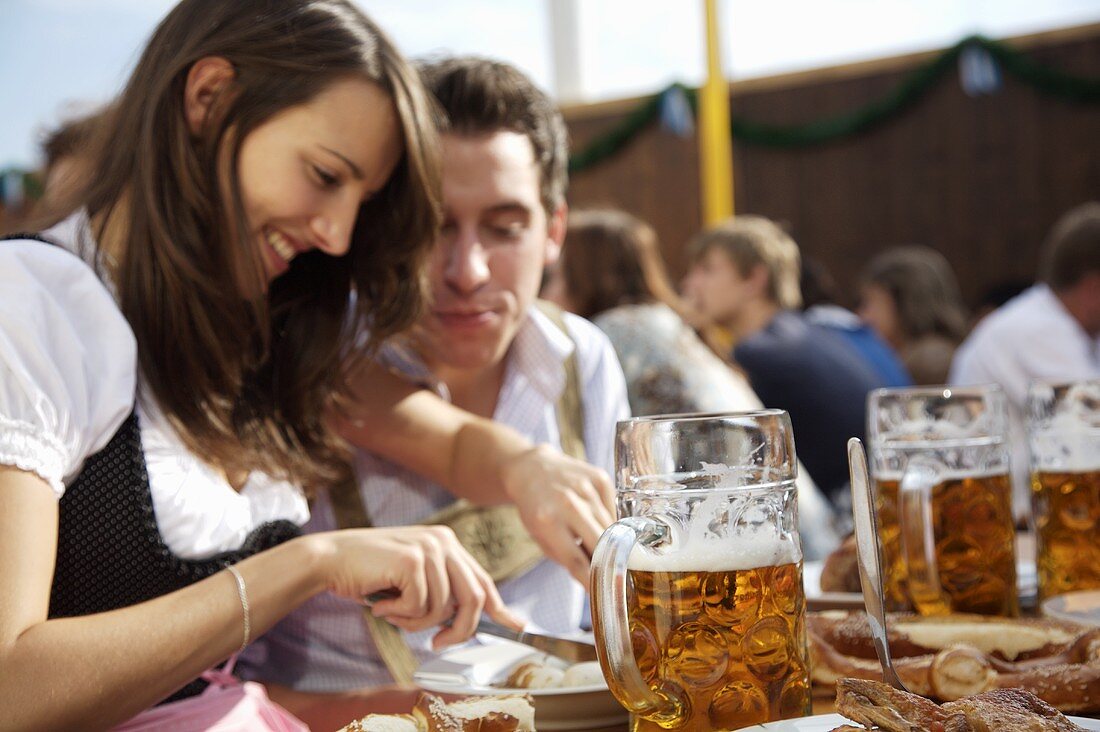 Mann & Frau in Tracht mit Schweinsbraten, Bier auf Volksfest