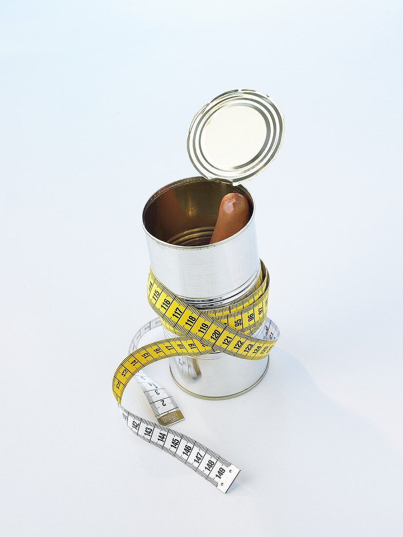 A sausage in a tin with a tape measure wrapped round it