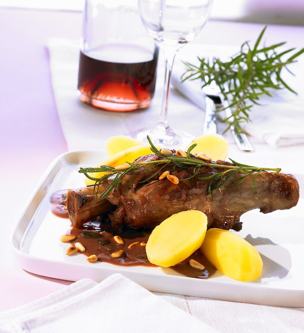 Lamb shank with pine nuts, pomegranate sauce and potatoes