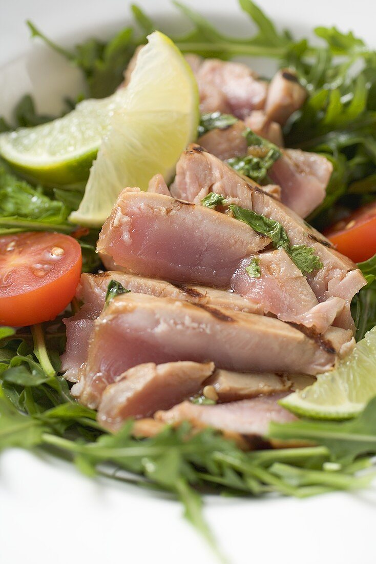 Sliced, grilled tuna on rocket salad with tomato