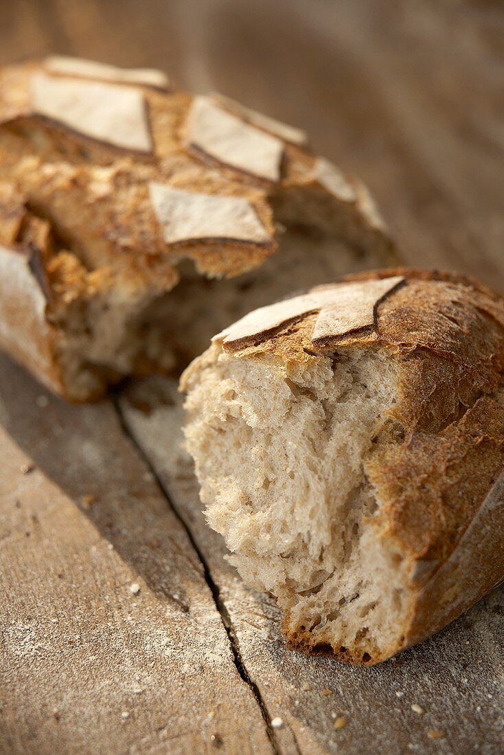 A broken loaf of rustic bread on wooden background