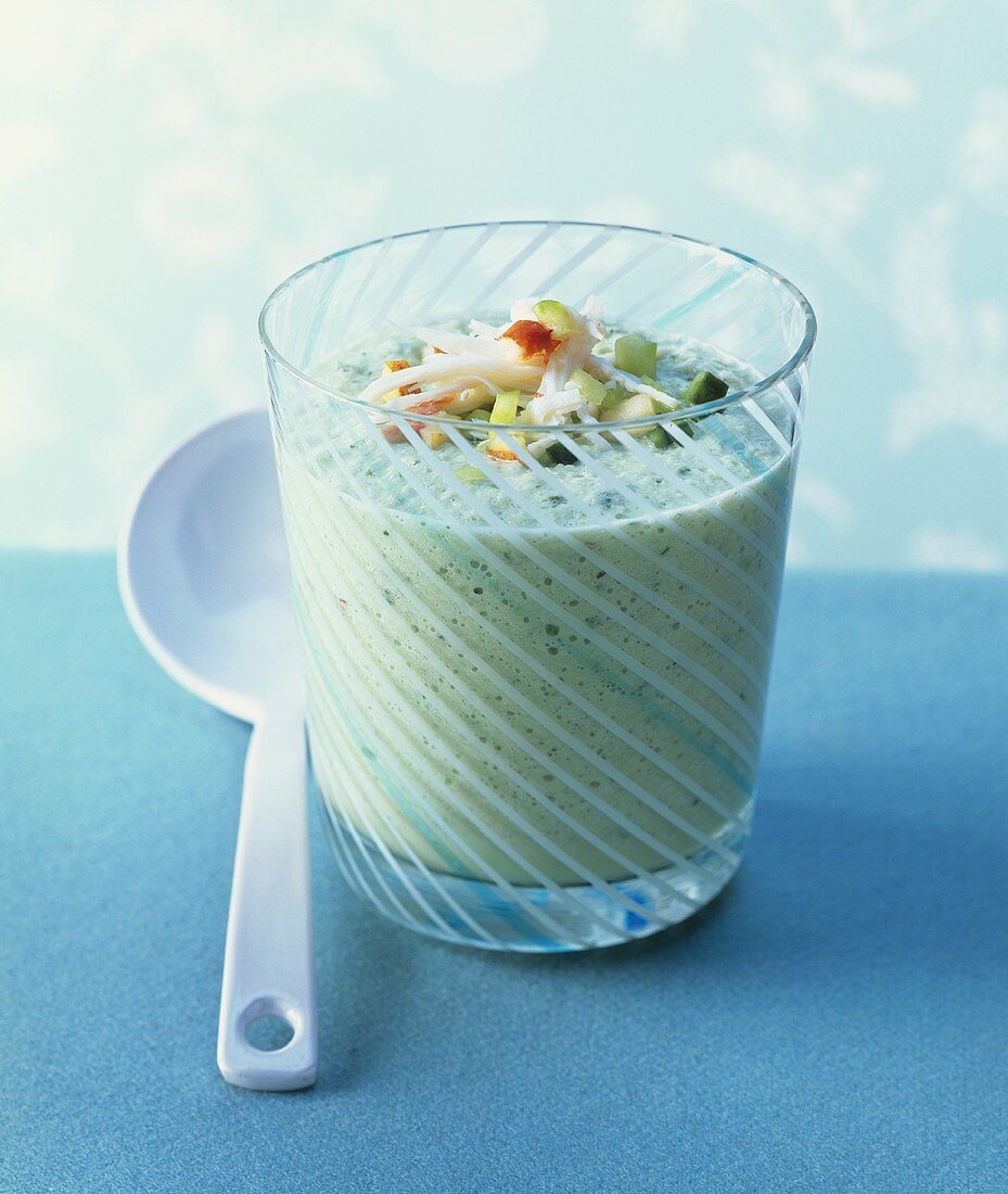 Cold, frothy cucumber soup in glass with crab salad