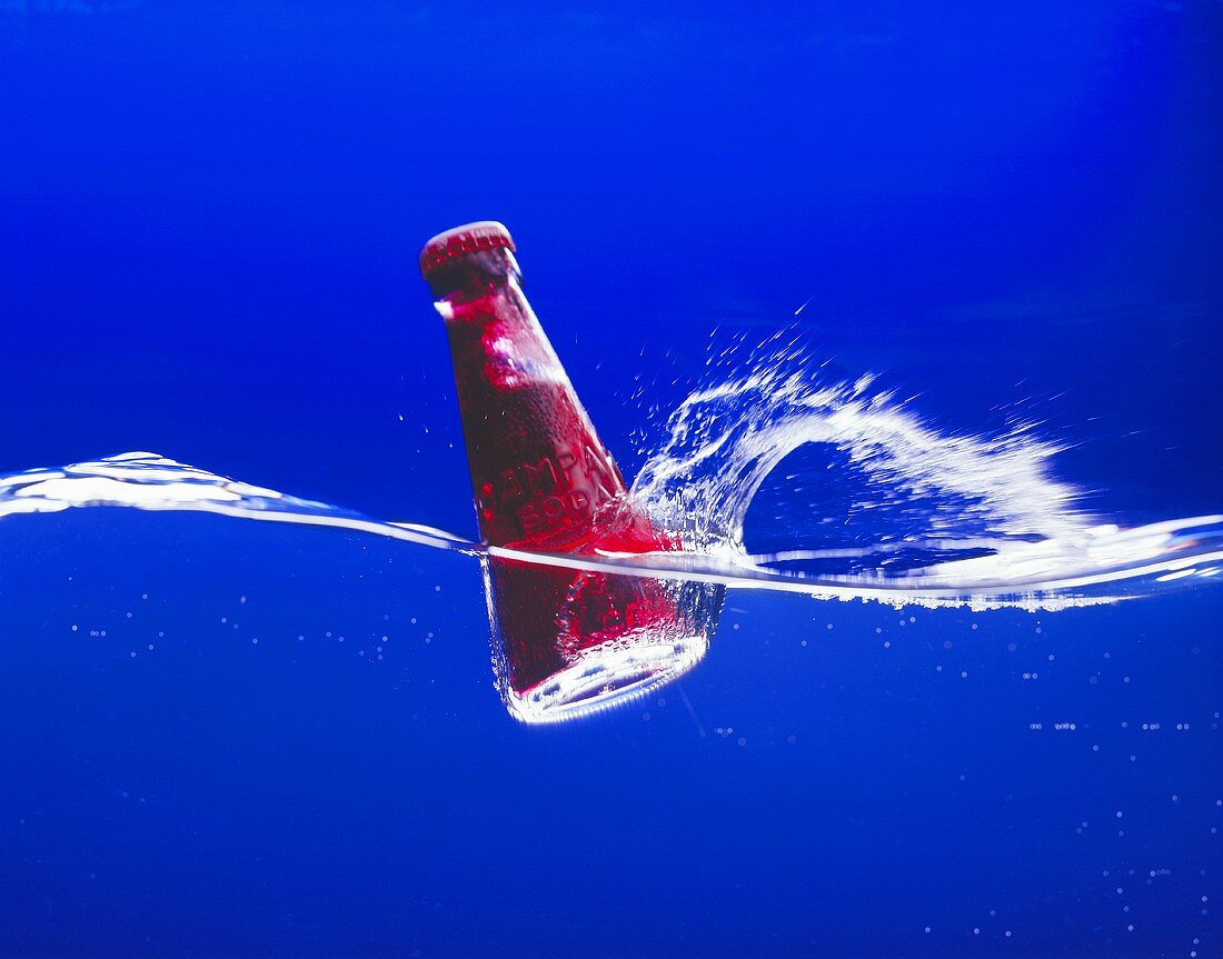 Ein Flasche Campari Soda fällt ins Wasser