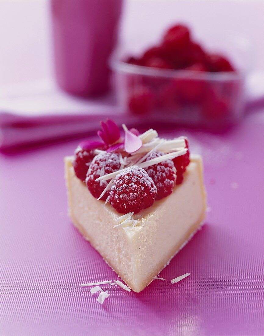 A piece of cheesecake with raspberries and white chocolate