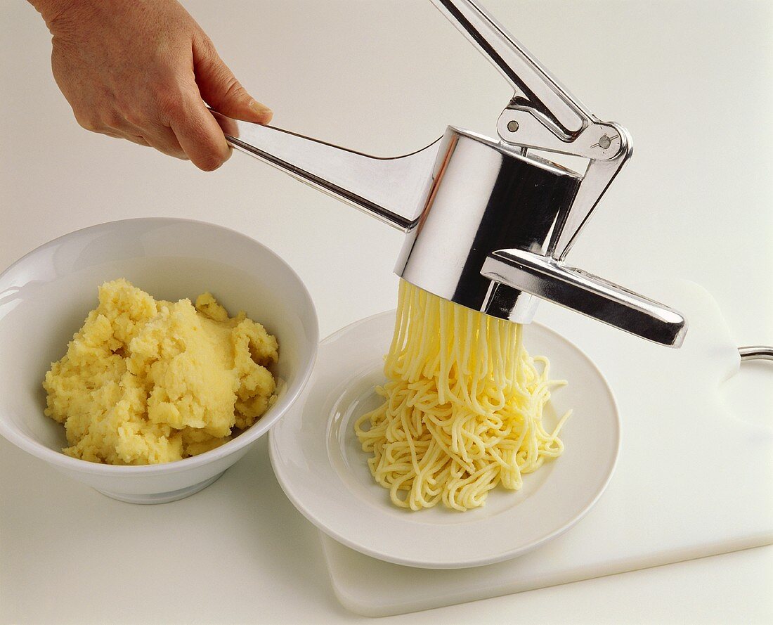 Making sweet spaghetti from semolina pudding with potato ricer