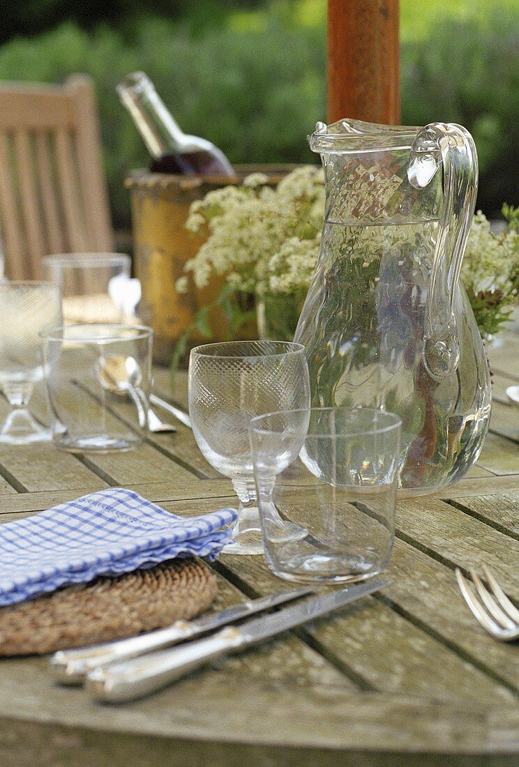 Gedeckter Tisch im Freien mit Wein, einem Krug Wasser, Gläser