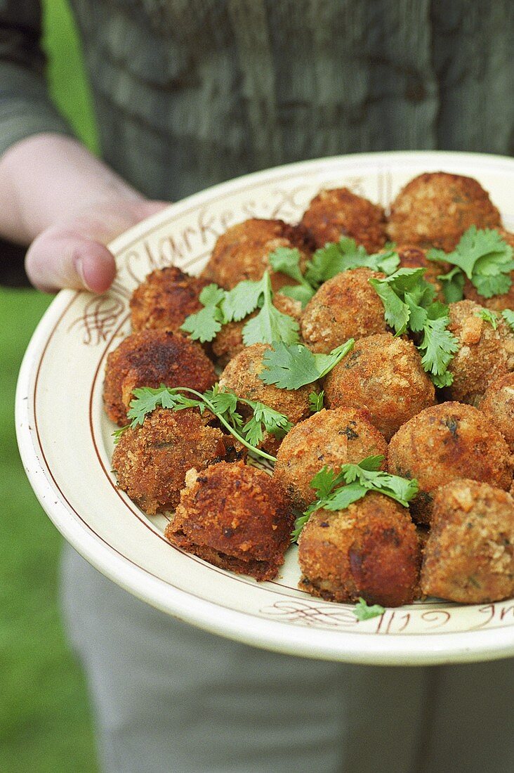 Woman carrying platter of deep-fried meatballs