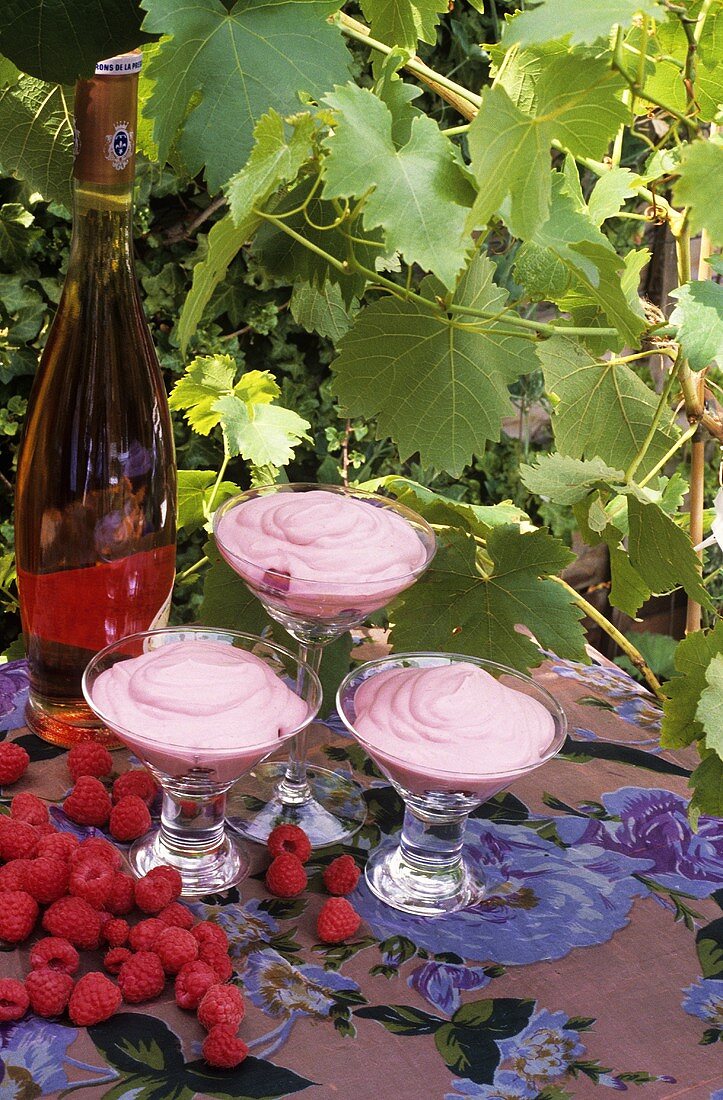 Raspberry cream in three glasses with a bottle of dessert wine