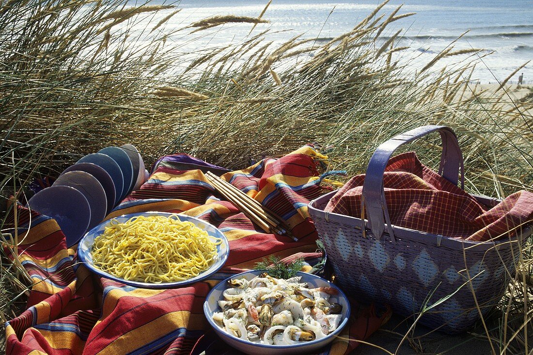 Picnic by the sea with seafood salad and noodles