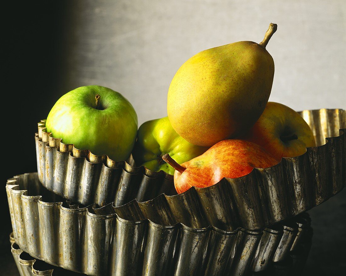 Äpfel und Birnen in gestapelten Tarteformen