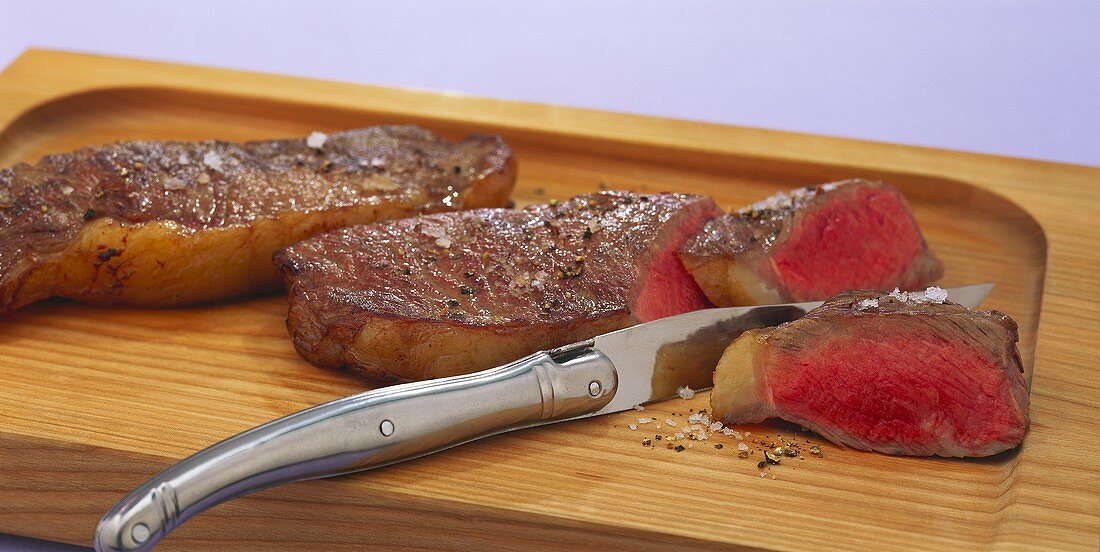 Fried sirloin steaks on wooden board