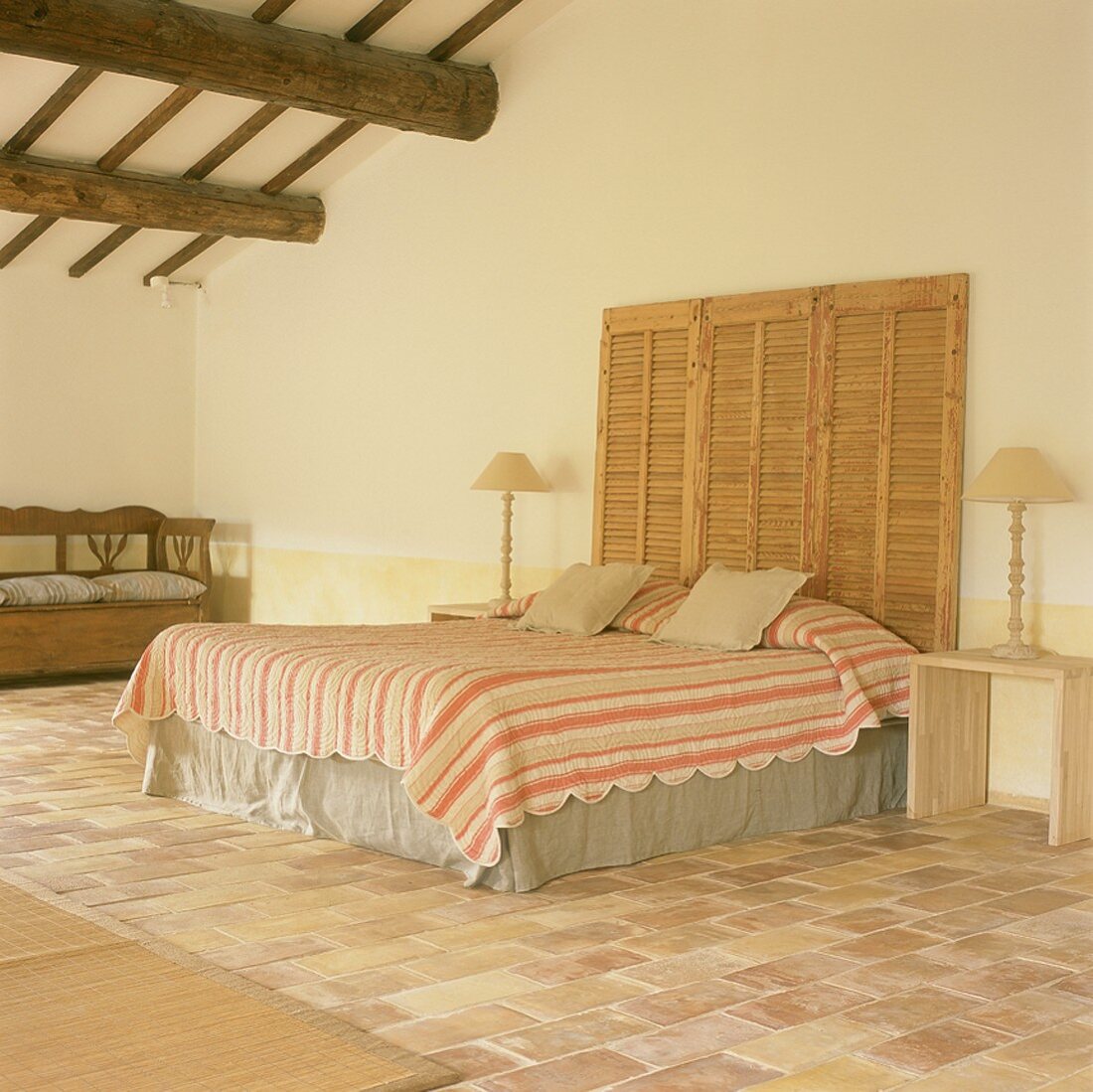 Schlafraum in ausgebautem Dach mit Doppelbett, Nachttischchen, Holzbank & Fliesenboden,