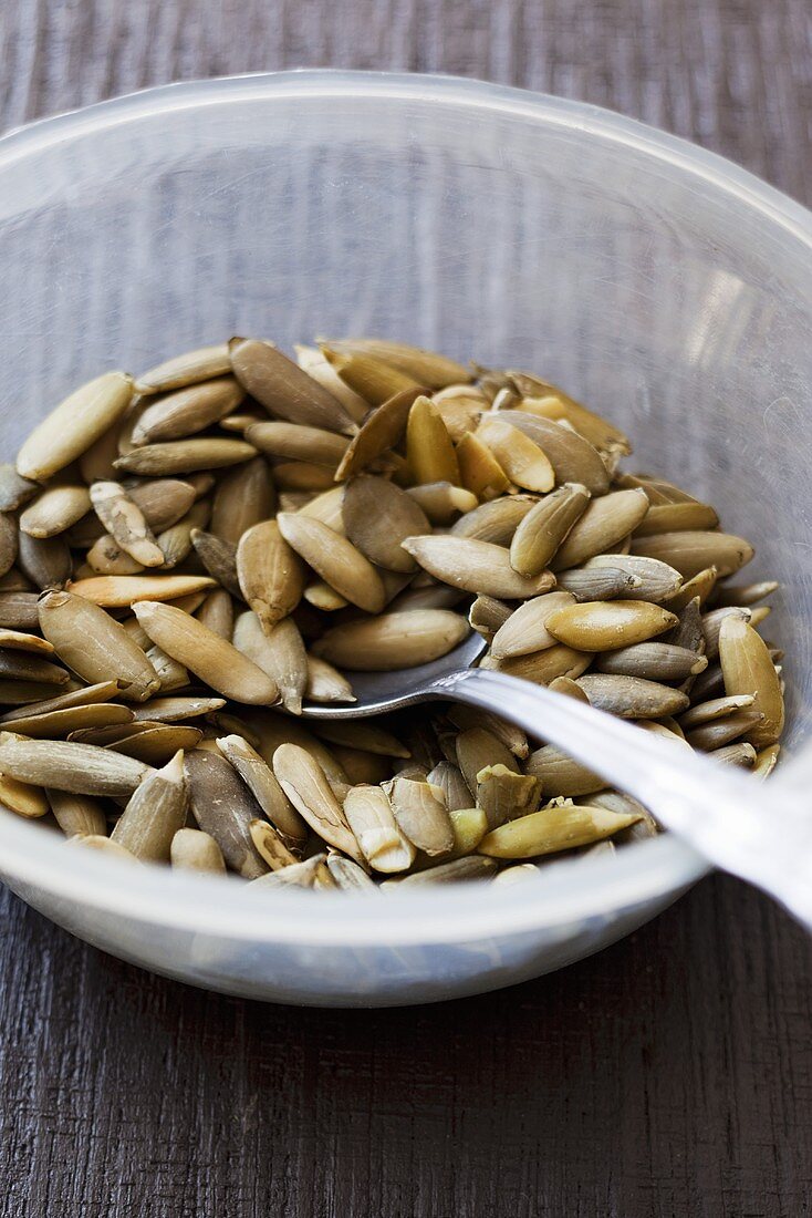 Pumpkin seeds in a glass bowl with a spoon