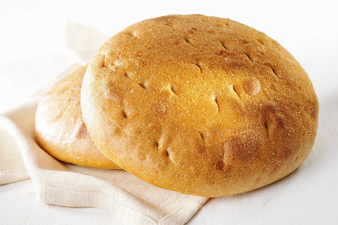 Two loaves of flat bread on a linen cloth