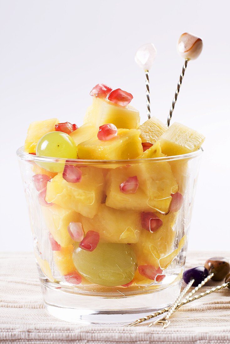 A fruit salad with pineapple, grapes and pomegranate seeds