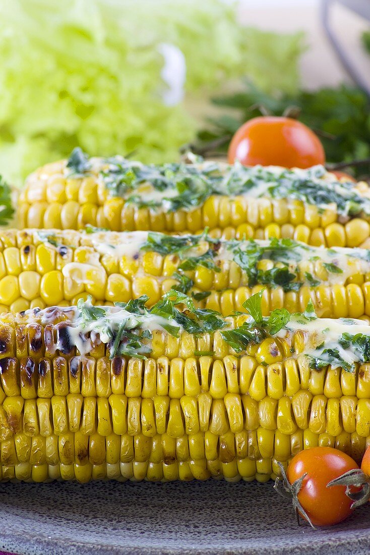 Drei gegrillte Maiskolben mit Kräuterbutter