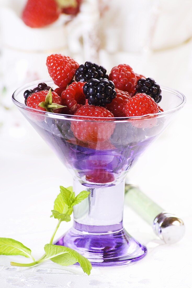 A glass bowl filled with raspberries and blackberries