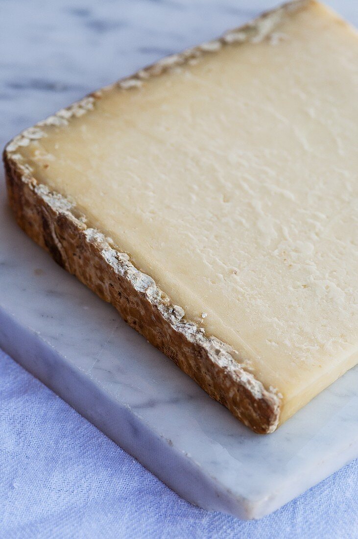 A piece of Cantal cheese on a marble slab