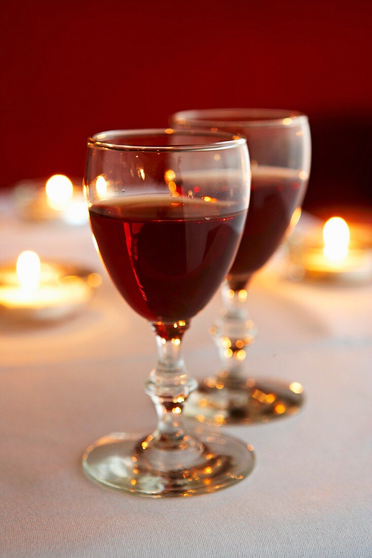 Two glasses of red wine on a candle lit table