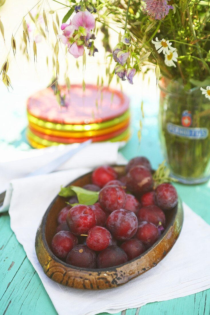 Fresh plums in a wooden bowl on a garden table