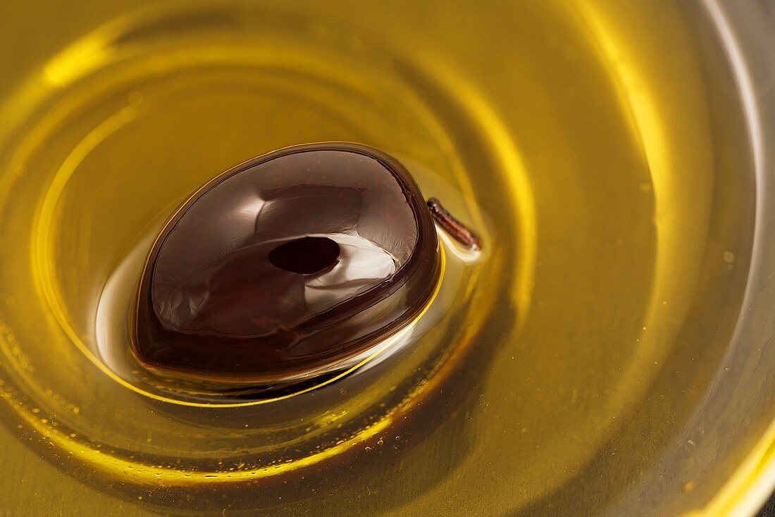 Ein Schälchen Olivenöl mit schwarzer Olive