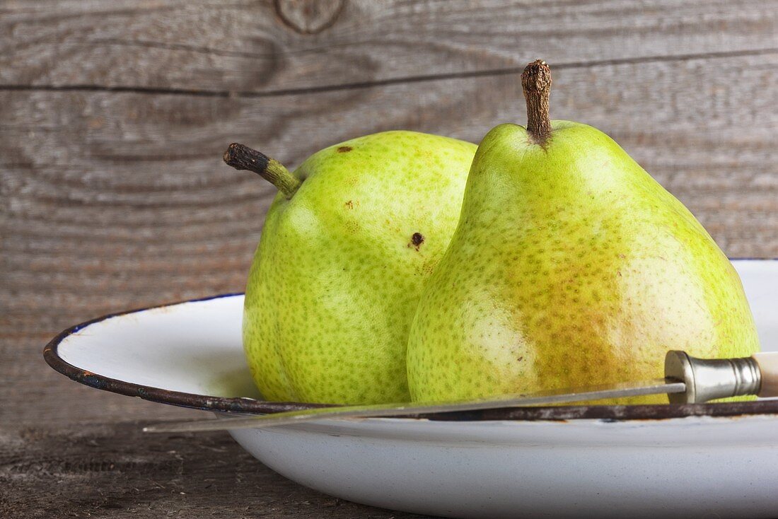 Two green pears on an enamel plate