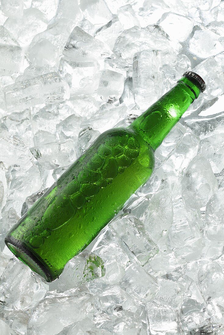 A green beer bottle on ice