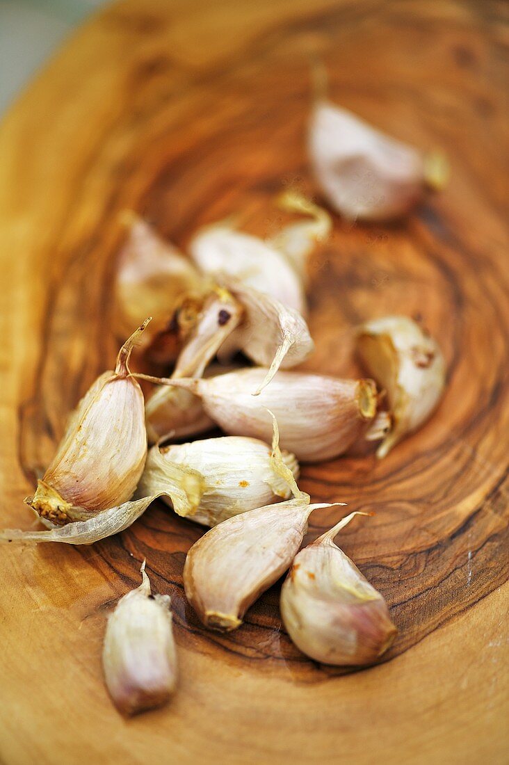 Roasted garlic cloves on a wooden plate