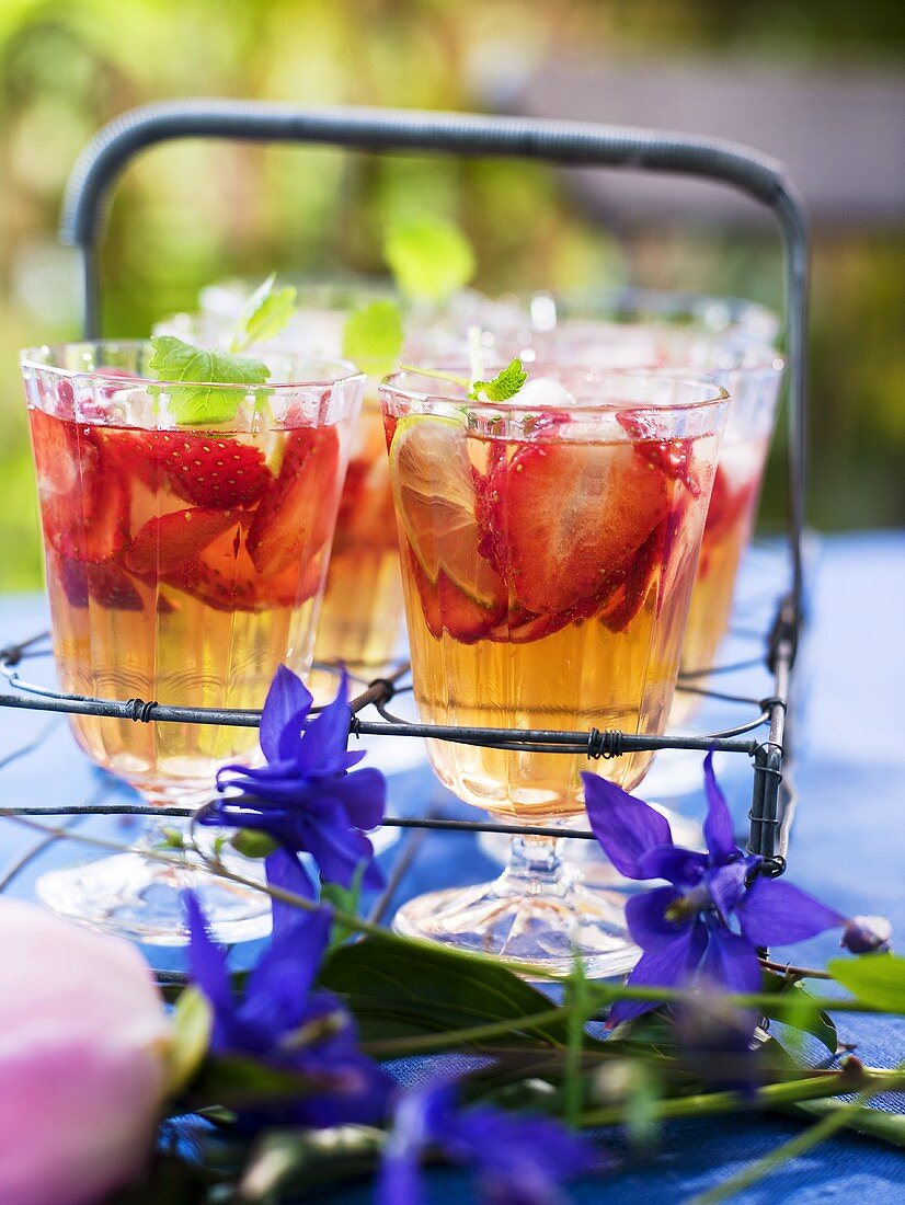 Glasses of strawberry punch with lemon balm and ice cubes
