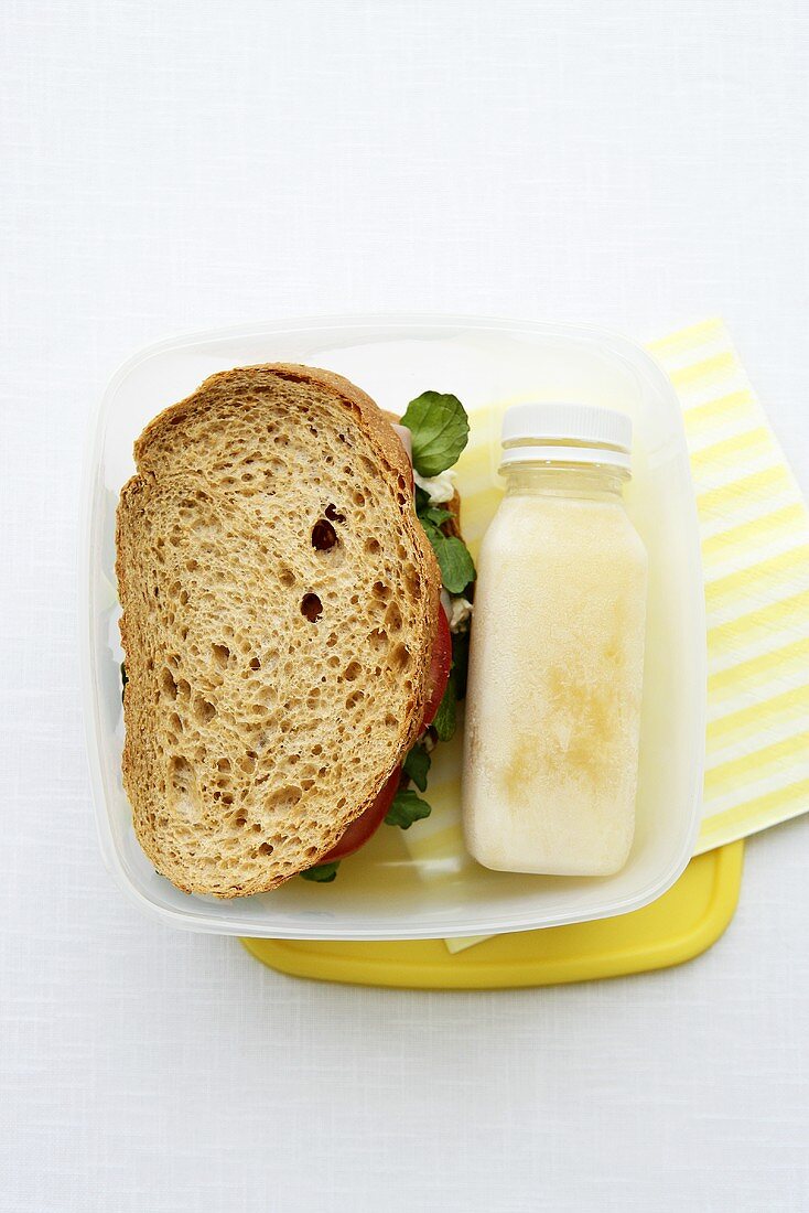 A lunchbox with a sandwich and a smoothie