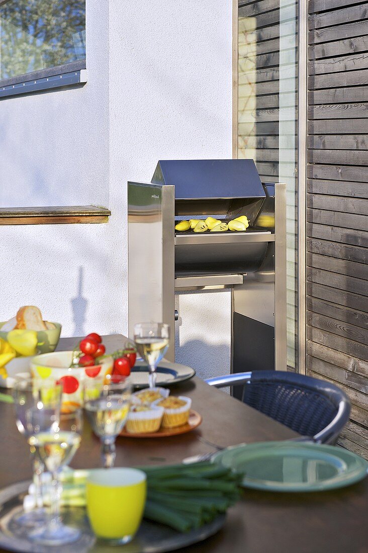 Gedeckter Tisch und ein Grill auf einer Terrasse