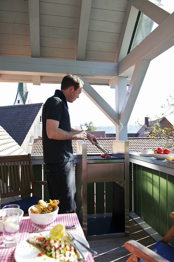 Mann grillt auf einer Terrasse