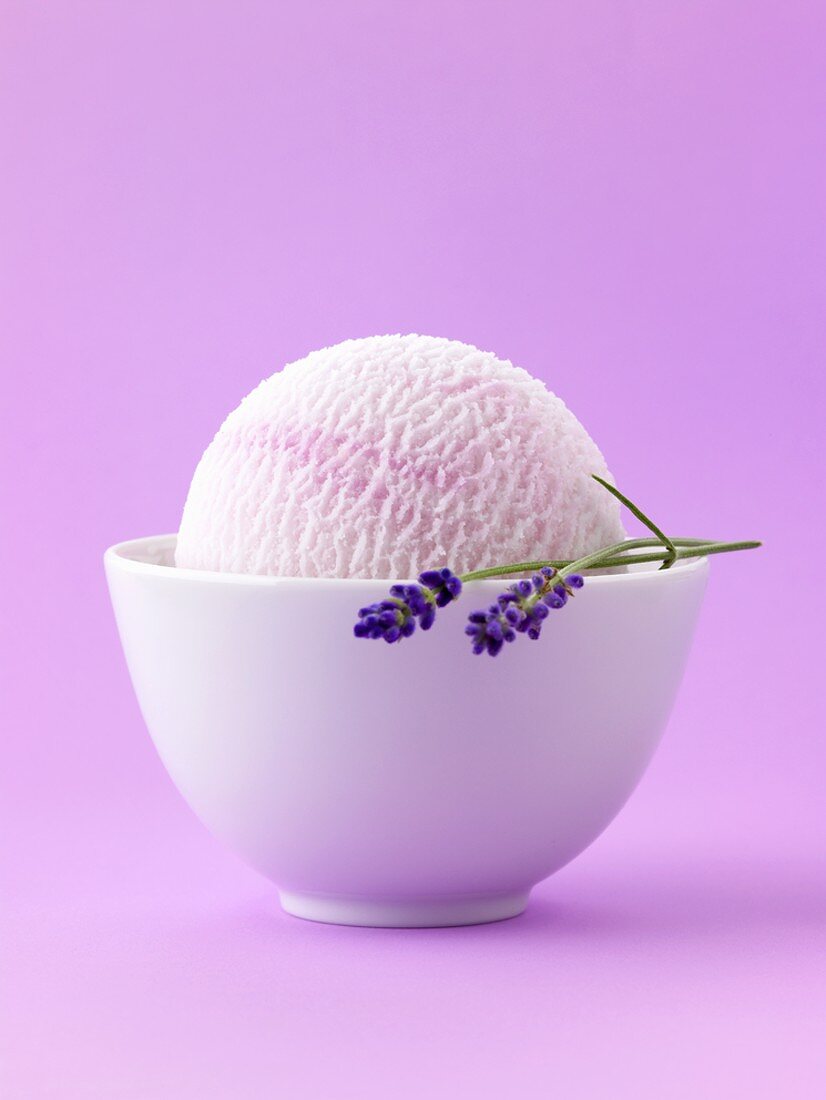 Lavender ice cream with lavender in white bowl