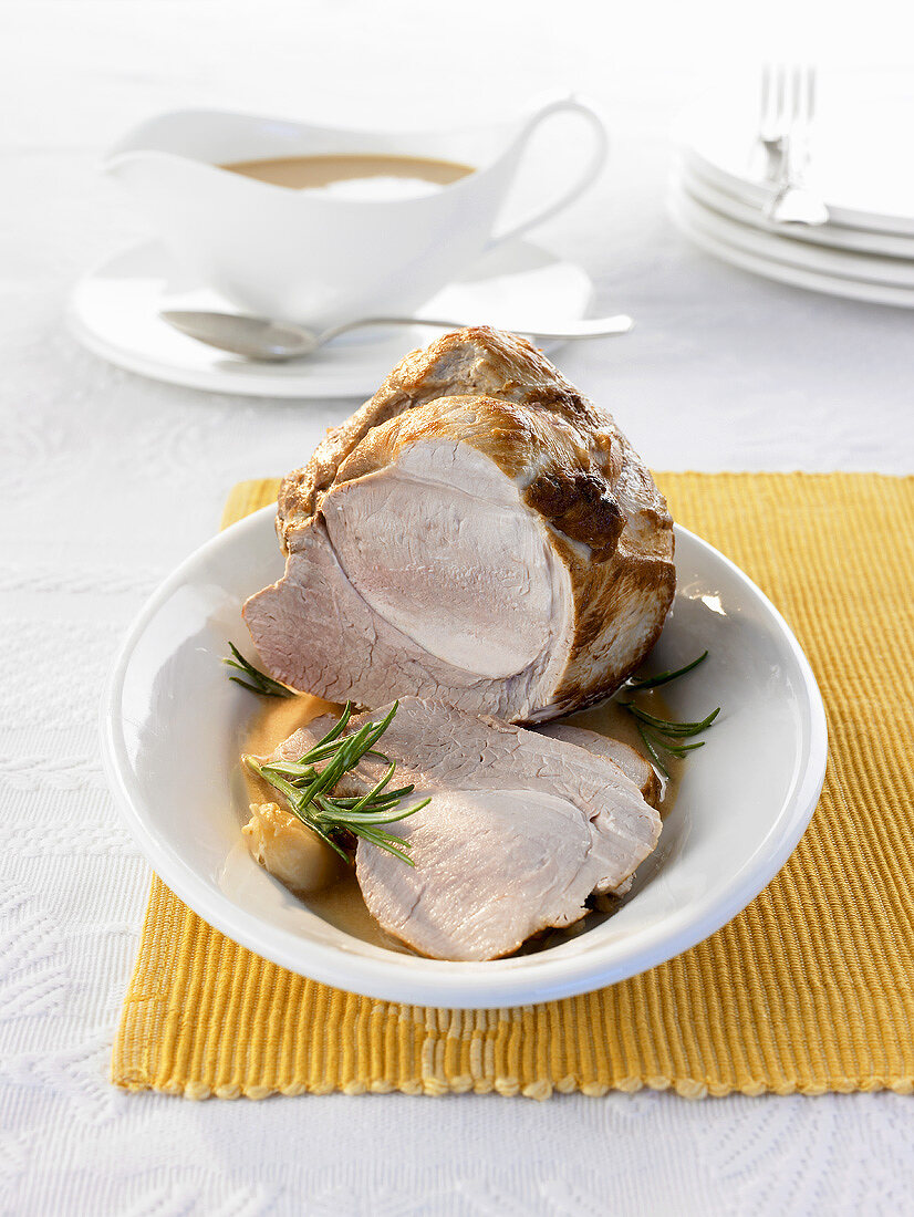 Roast pork, partly carved, with gravy in gravy boat