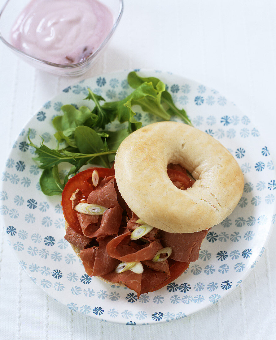 Bagel mit Pastrami, Tomate, Frühlingszwiebeln und Rucola