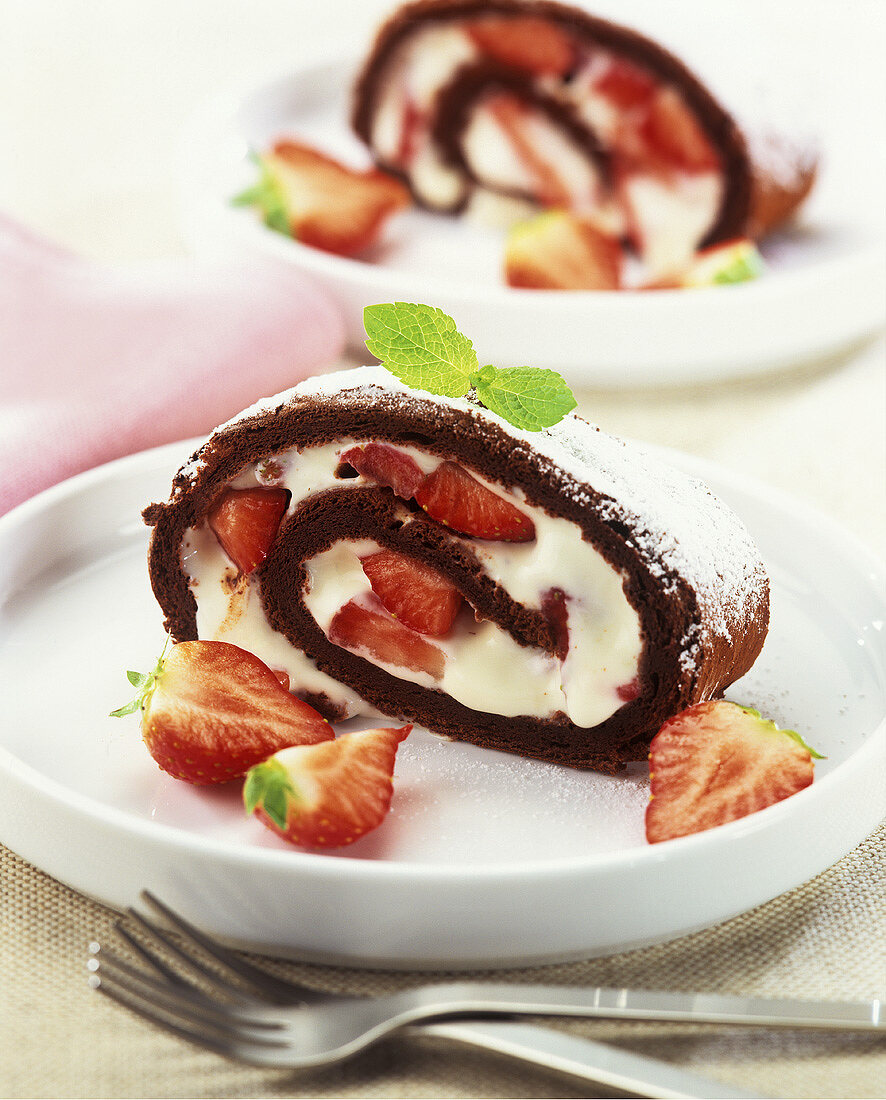 Zwei Stücke dunkle Biskuitroulade mit Erdbeer-Cremefüllung
