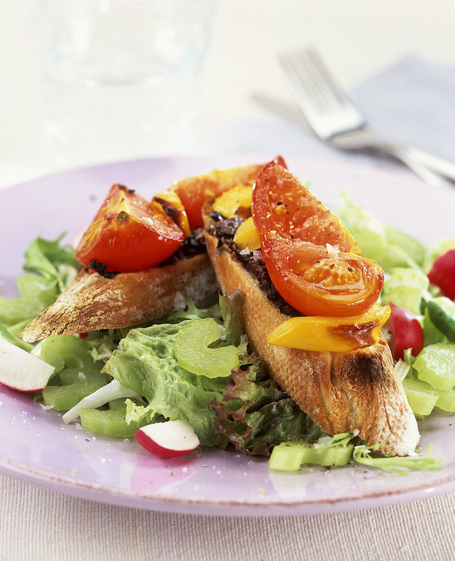 Baguette topped with tapenade, peppers, tomato on mixed salad