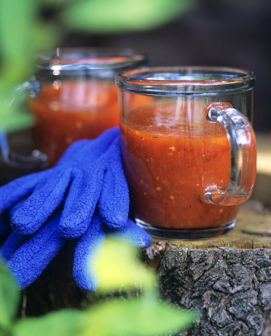 Tomaten-Paprika-Suppe in zwei Glastassen mit Handschuhen