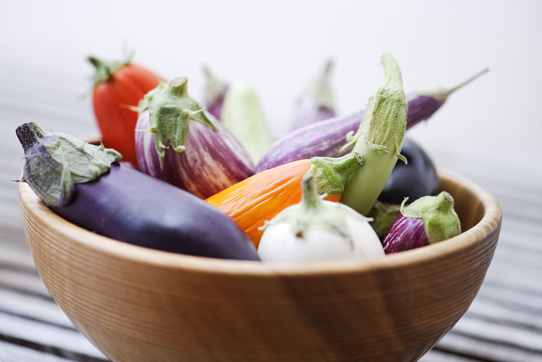 Various types of aubergines in a wooden bowl