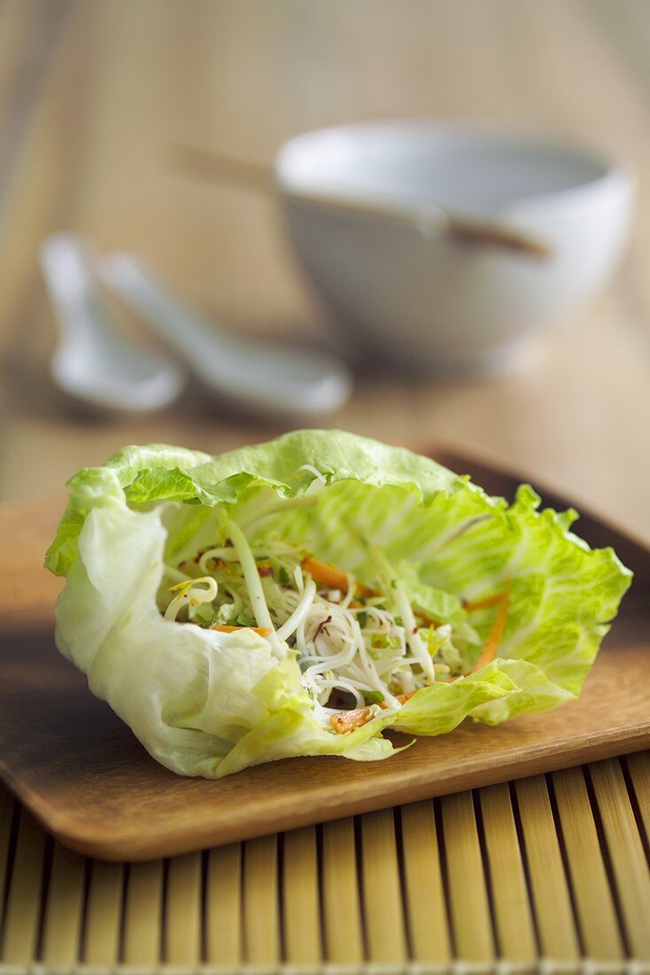 Sprout salad in a lettuce leaf on a wooden board