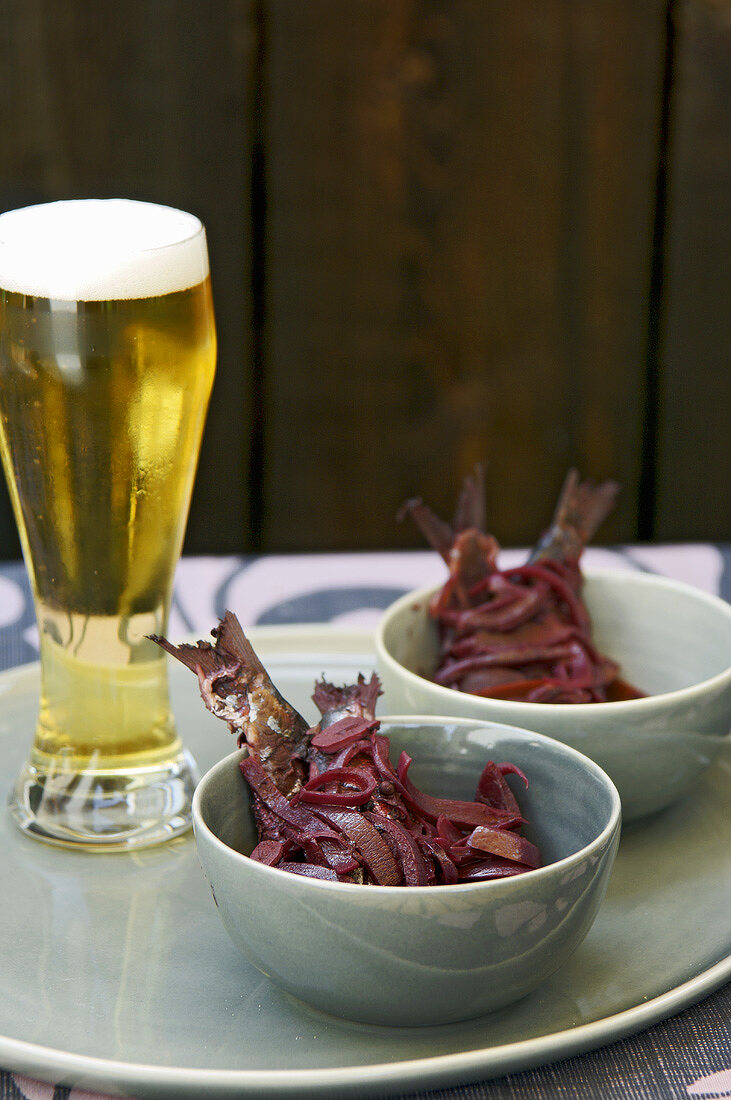 Sardinen in Rotweinmarinade auf einer Platte mit Bier