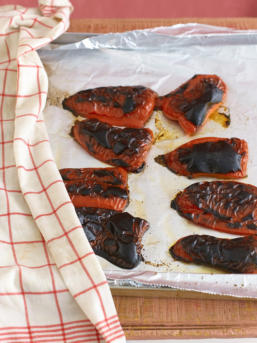 Grilled, quartered red peppers on a baking tray